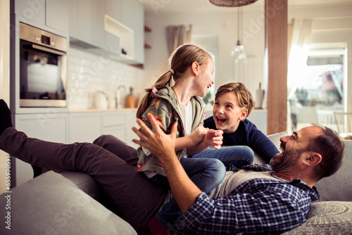 Happy young caucasian family being playful and having fun together on the couch in the living room at home © Geber86