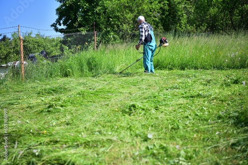 Obraz na płótnie The gardener mows the grass in a modern way with a petrol mower w salonie