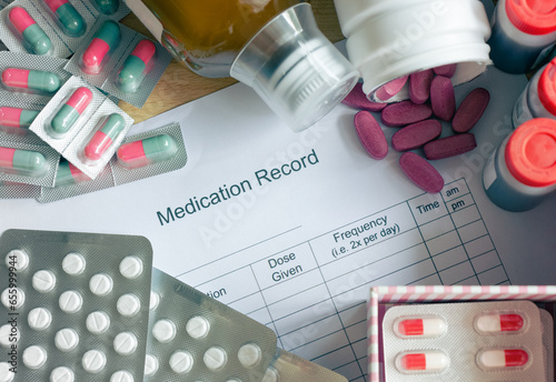 A patient's daily routine managing multiple medications. The central focus is on a medication schedule chart surrounded by an array of different medicines. Selective focus.

