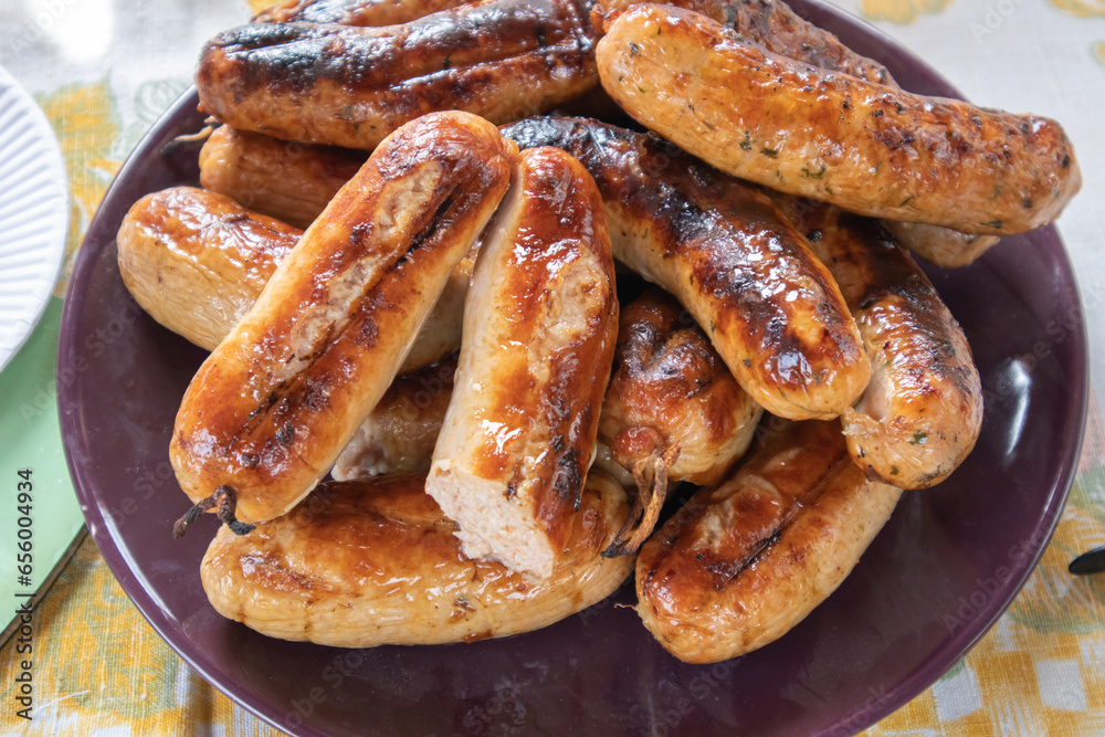 Grilled barbecue sausages on a plate, top view, close-up