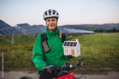 Portrait of a beautiful cyclist standing in front of solar panels at a solar farm.