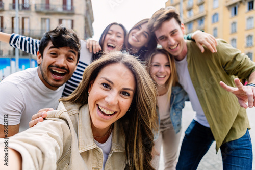 Young group of happy people having fun together outdoors. Multicultural student friends taking selfie portrait together while enjoying travel vacation. Youth community and friendship concept.