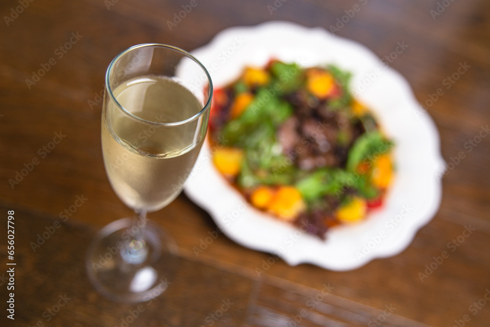 top view of a warm salad with mushrooms and herbs in a white plate with a glass of wine on the table top view of a warm salad with mushrooms and herbs in a white plate with a glass of wine on the table