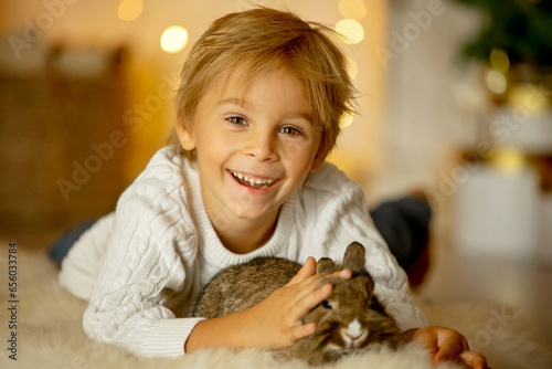 Beautiful little blond child, cute boy, holding small pet rabbit