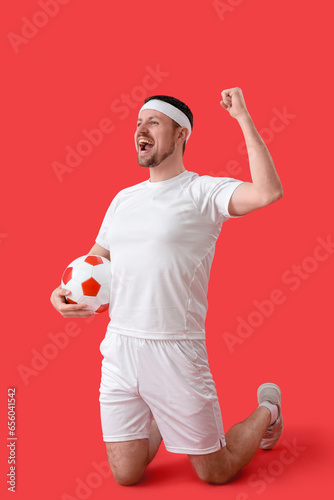 Happy soccer player with ba...