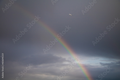 Rainbow and airplane on stormy dark sky background