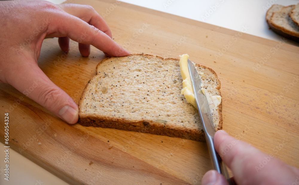 Spreading butter onto sliced brown bread Spreading butter onto sliced brown bread