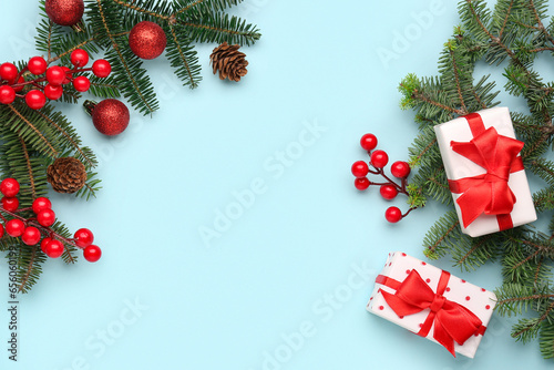Christmas tree branches with gift boxes, balls and rowan on blue background