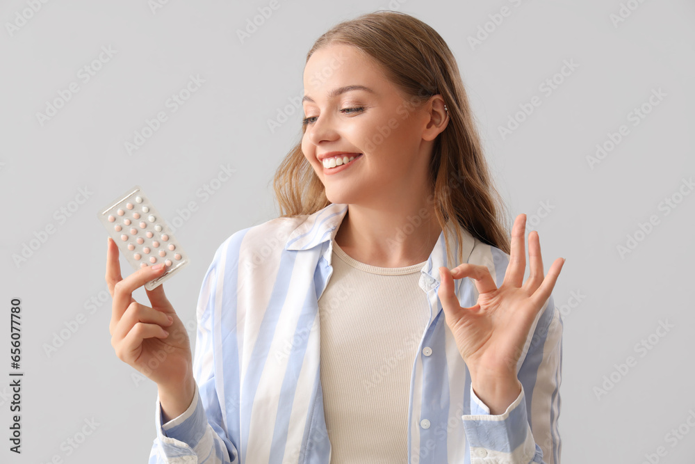Young woman with contraceptive pills showing OK on light background, closeup Young woman with contraceptive pills showing OK on light background, closeup
