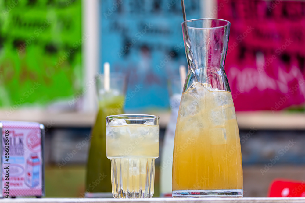 Refreshing cold green lemonade in a carafe on the table on the background of nature. Fresh drinks whith ice. Lemonade with lemon, lime and herbs