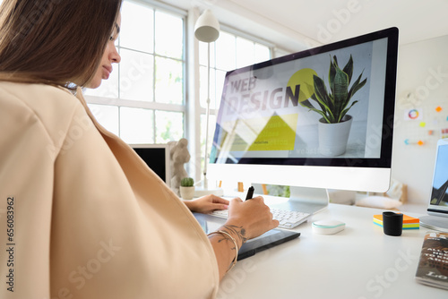 Female interior designer working with graphic tablet at table in office, closeup