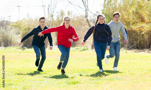 Group of joyful teenagers running down in the spring park