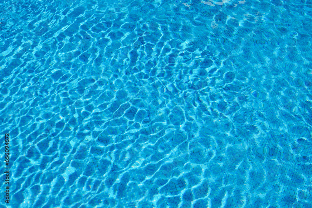 Blue water in summer pool on bright sunny day. Background. Clean transparent water with reflection.