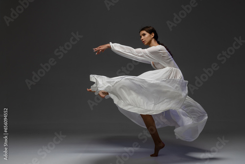 Fototapeta Naklejka Na Ścianę i Meble -  girl dancer in a long beige dress on a dark background