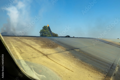 upper surface of right wing of B-24 liberator on sunny day with smoke rising from inboard engine starting