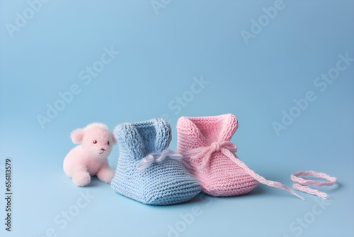 Cute pink knitted baby booties on a blue background with copyspace. Gender Reveal concept, Flat lay, top view, for banner background photo