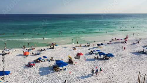Colorful tents, beach lounge chairs, canopy and crowded of people swimming, relaxing, walking along white sandy shoreline with turquoise water, South Walton beach, Destin, Florida photo