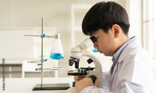 Children scientist learning on biology and chemistry in the laboratory. A STEM education learning concept. An Asian student boy using microscope in a STEM class lab at school.