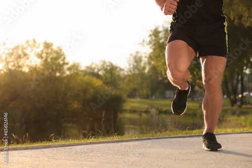 Man running near pond in park on sunny day, closeup. Space for text