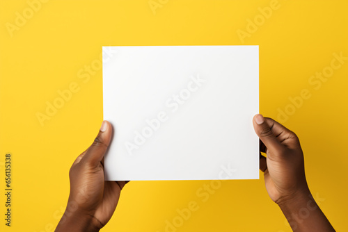Person holding a white piece of paper in their hands on a yellow background 