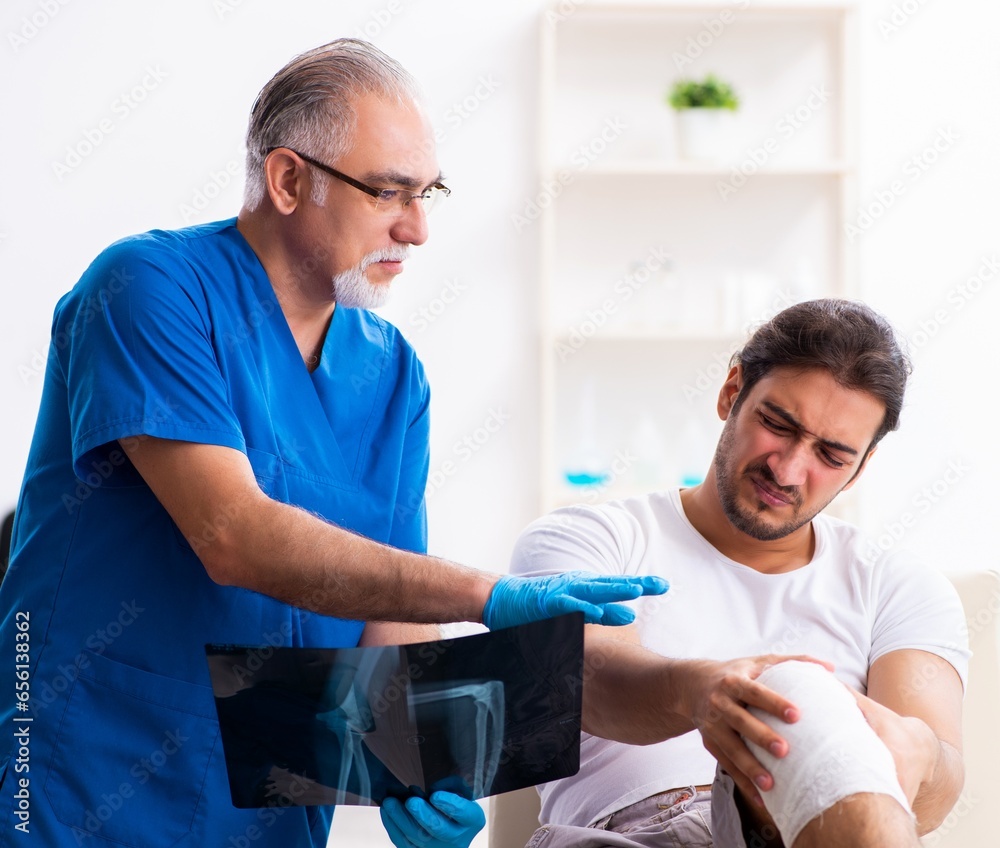 Leg injured man visiting old doctor in first aid concept Leg injured man visiting old doctor in first aid concept