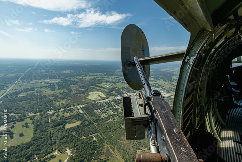 looking out the right waist of a B-24 bomber on a sunny day with machine gun in the foreground