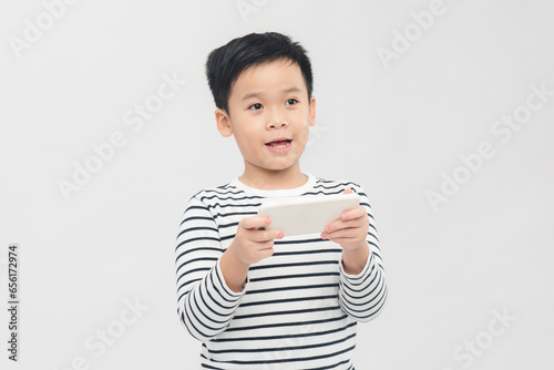 Emotional little boy playing with smartphone on white background