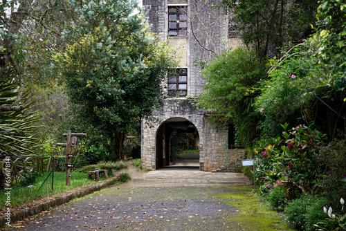 Historic stonework church entrance surrounded by trees and garden