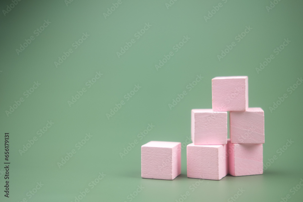 Stacked pink colored wood building blocks on a green background Stacked pink colored wood building blocks on a green background