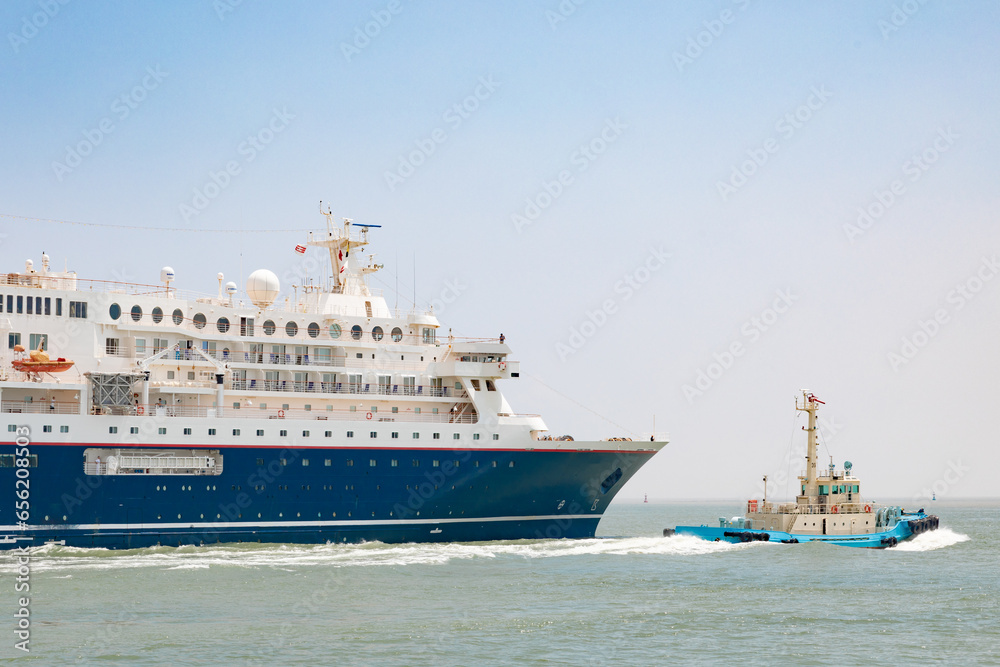 A departing huge cruise ship guided by a tugboat at Yokkaichi Port, Yokkaichi, Mie, Japan A departing huge cruise ship guided by a tugboat at Yokkaichi Port, Yokkaichi, Mie, Japan