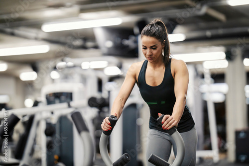 A strong woman is pushing weights in a gym during her training.