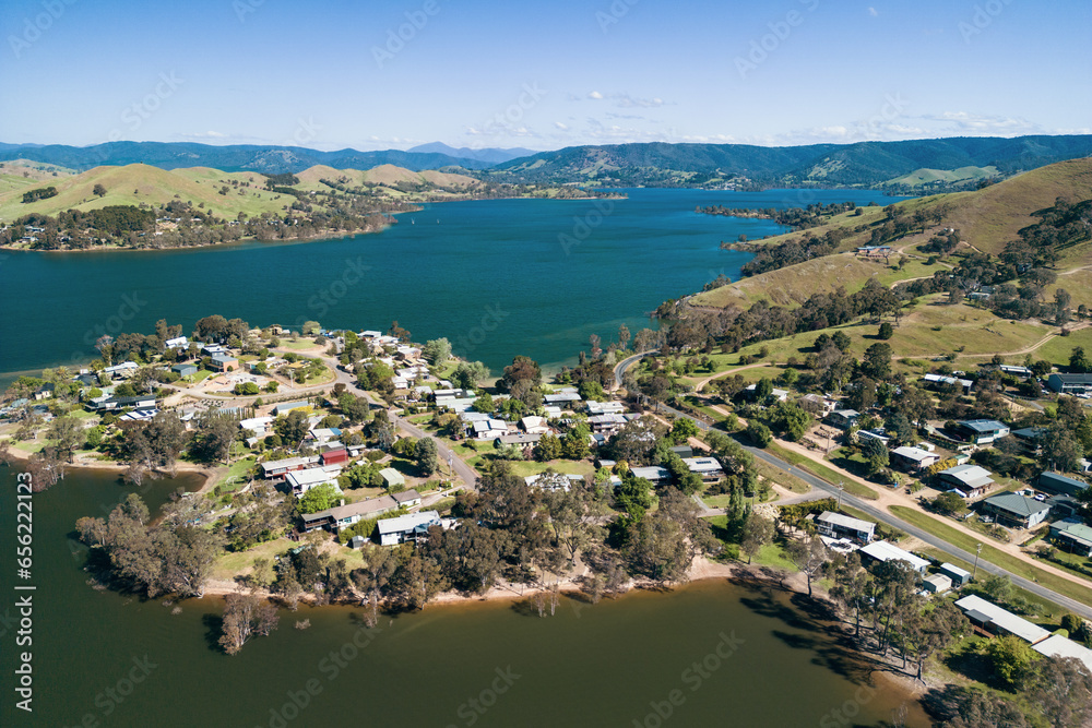 An aerial view of residential housing nestled amongst gumtrees and hills on the edge of Lake Eildon.