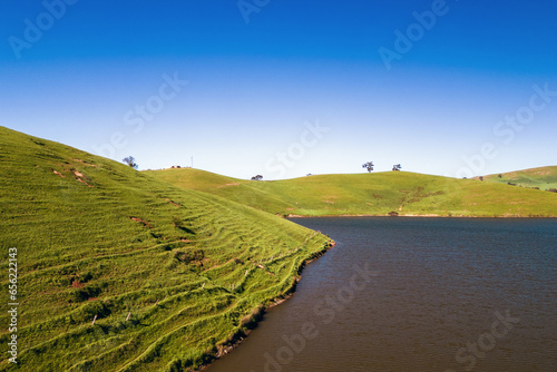 A view of grass covered hills on the edge of Lake Eildon.