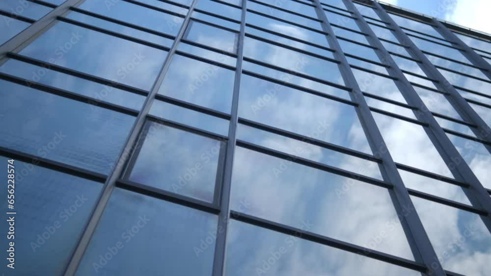 Smooth camera movement in front of the windows of an office building reflecting a sunny blue sky with white puffy clouds. 4k Smooth camera movement in front of the windows of an office building reflecting a sunny blue sky with white puffy clouds. 4k