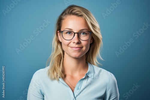 Portrait of a beautiful young businesswoman wearing glasses over blue background.