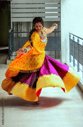traditional full flare ghaghra choli outfit in gujarati look for folk dance and garba in navratri. woman wearing beautiful hand made oxidized ornaments jewellery and dancing on garba beats.  photo