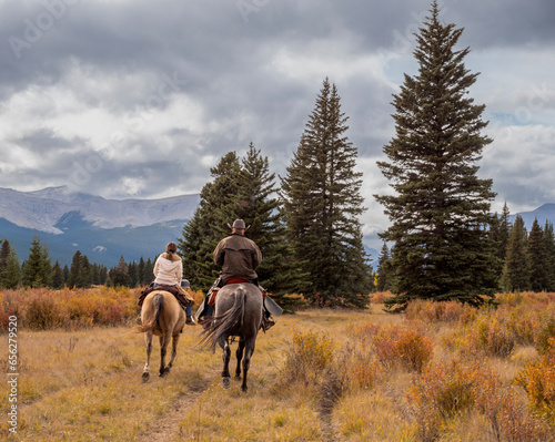 A man and woman horseback riders make their way along a trail in the Ya Ha Tinda Ranch in Alberta, Canada during autumn photo