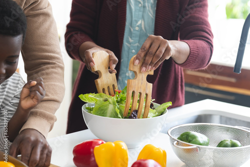 African american grandmother mixing salad in kitchen