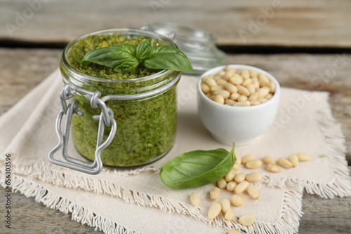 Delicious pesto sauce, pine nuts and basil leaves on wooden table, closeup