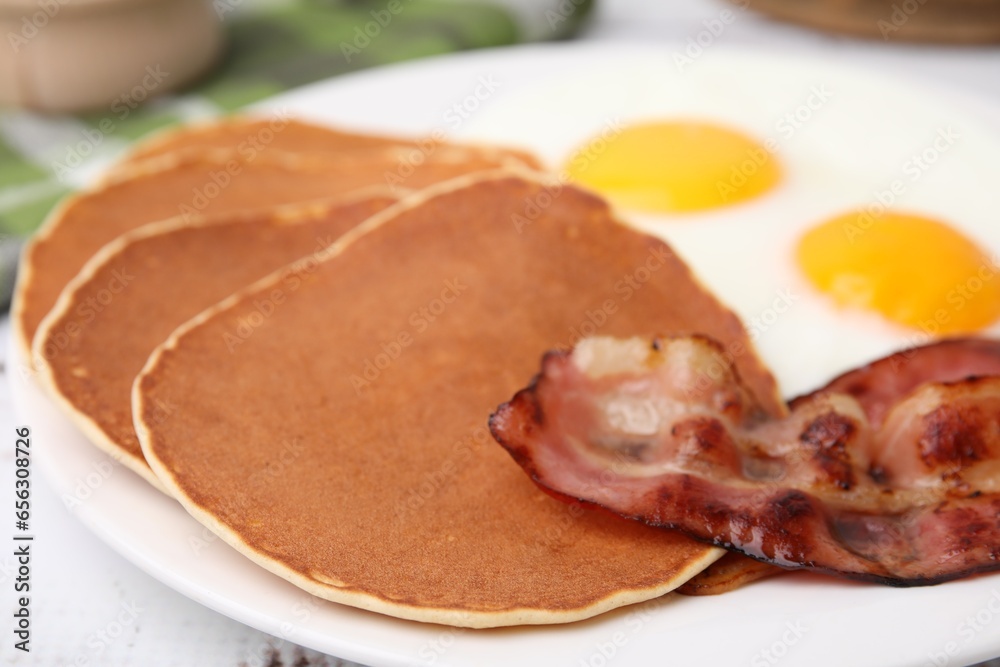 Tasty pancakes with fried eggs and bacon on white wooden table, closeup Tasty pancakes with fried eggs and bacon on white wooden table, closeup