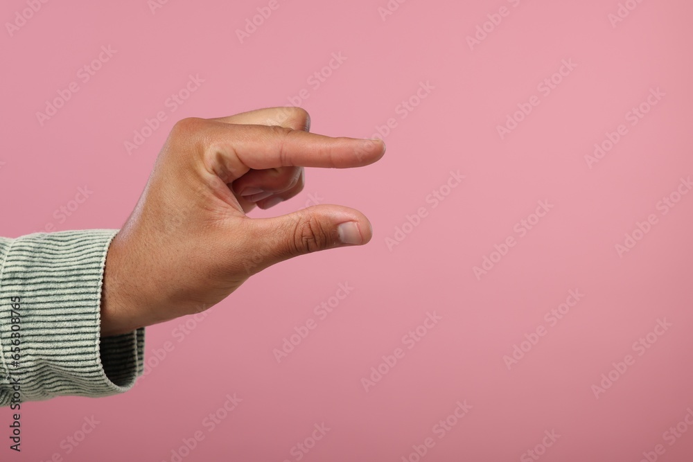 Fototapeta premium Man holding something in hand on pink background, closeup. Space for text