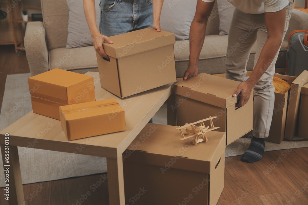 Beautiful young couple in love having fun unpacking things from cardboard boxes while moving in together in their new apartment