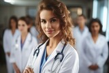 Attractive female doctor standing on front of medical group at hospital corridor.