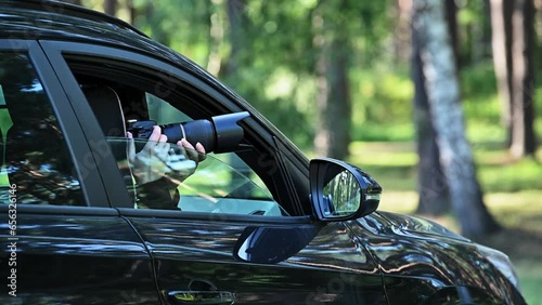 Spy with camera in car. A paparazzi sits in his car and takes pictures of a famous person.