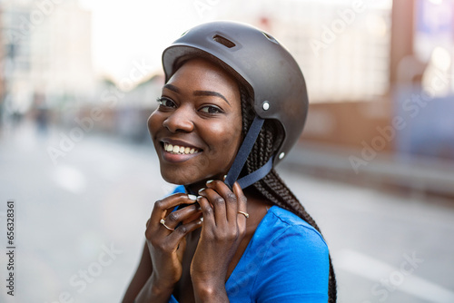 Young woman putting her cycling helmet on
