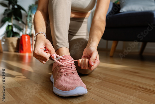 Close-up view of female hands tying laces of her sport shoes before home workout exercise routine. Motivation  healthy lifestyle and fitness concept.