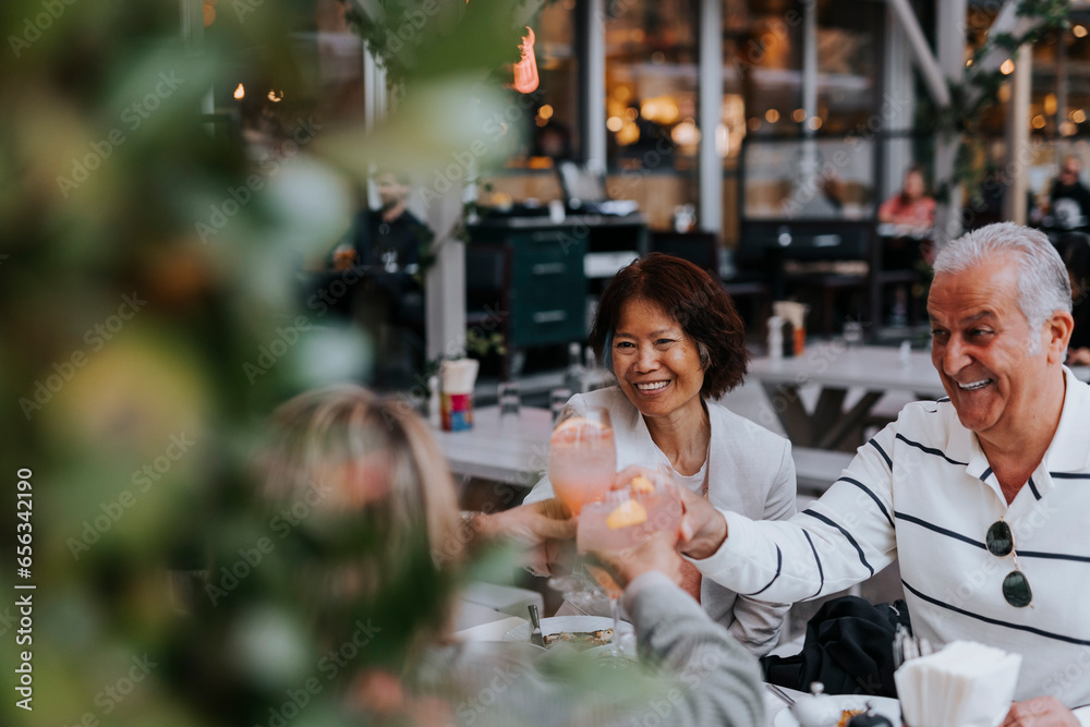 Smiling senior man toasting drinks with male and female friends at restaurant Smiling senior man toasting drinks with male and female friends at restaurant