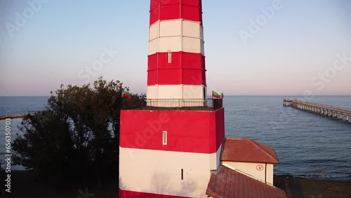 Aerial drone footage of the Shabla lighthouse, beach and surf. Top down high angle shot of green sea and red white vintage lighthouse at the coast of Bulgaria.
 photo