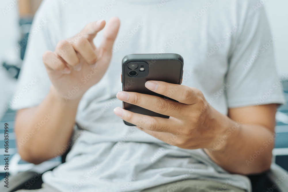 Hands of Asian man holding checking touching scrolling smartphone from bed room Hands of Asian man holding checking touching scrolling smartphone from bed room