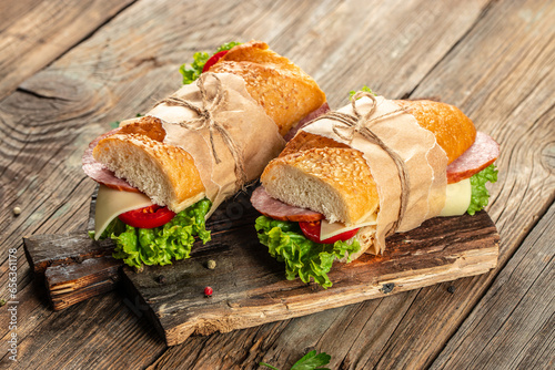 Healthy sandwich salami, tomato, lettuce and cheese on a wooden board. banner, menu, recipe place for text, top view